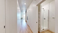 Located at 757 N Grant St in Denver's Capitol Hill neighborhood, this modern studio unit offers a thoughtfully designed single-floor layout. Light hardwood-style flooring runs continuously throughout the space, creating a cohesive and clean aesthetic. The open living area is bright and airy, with recessed lighting and a large window that frames views of the surrounding Denver cityscape, allowing ample natural light to fill the room.

The kitchen is a standout feature, outfitted with dark charcoal cabinetry, a tiled backsplash, a stainless steel sink, and a full suite of stainless and black appliances including a range, microwave, and French door refrigerator. A dedicated alcove houses a stacked washer and dryer unit, providing the convenience of in-unit laundry.

The bathroom is finished in a clean, contemporary style with wood-look tile flooring, a glass-enclosed walk-in shower with tiled walls, a dark-vanity cabinet with an undermount sink, and a full toilet — all accented by brushed nickel hardware. A hallway connects the main living areas to a closet, offering practical storage. The overall design is modern and minimal, making efficient use of space with a neutral palette and quality finishes throughout.