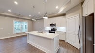 Located at 5833 Evans Farm Dr. in Lewis Center, Ohio, this single-floor home offers a well-designed open layout with consistent neutral tones and quality finishes throughout. The interior is unified by durable hardwood-style flooring in the main living areas and plush carpet in the bedrooms, creating a comfortable and cohesive aesthetic.

The kitchen is a standout feature, showcasing white shaker-style cabinetry, crisp white quartz countertops, a large center island with an undermount sink, and stainless steel appliances including a range, microwave, and refrigerator. Polished chrome pendant lights hang above the island, complementing the recessed lighting and tray ceiling detail that add architectural character to the space.

A wide hallway connects the living areas to the private rooms, with recessed lighting guiding the way. The primary bathroom features a glass-enclosed tile shower, a double-sink vanity with white cabinetry, and direct access to a walk-in closet. A secondary full bathroom offers a tub/shower combo, white vanity, and matching clean finishes.

The bedrooms are bright and well-sized, each with large windows that welcome natural light and views of the surrounding neighborhood. A dedicated laundry room with washer and dryer hookups adds everyday convenience. The living area at the end of the hallway opens to French doors, inviting natural light deep into the home.