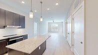 Located at 1110 Metropolitan Ave in Summerville, SC, this well-appointed 2-bedroom, 2-bathroom residence offers a thoughtfully designed single-level layout. The open-concept kitchen and living area forms the heart of the home, where a striking kitchen showcases dark espresso cabinetry, granite countertops, a large center island with pendant lighting, and stainless steel appliances including a French door refrigerator and dishwasher. Light wood-style flooring flows seamlessly throughout the entire residence, complementing the neutral, warm-toned walls. The spacious living area is brightened by natural light from a large window and is equipped with a ceiling fan. A glass-panel door provides additional light and access to the exterior. Both bedrooms are generously sized, each featuring ceiling fans, multiple windows with blinds, and ample natural light. The expansive primary bedroom includes a walk-in closet with built-in wire shelving. The two bathrooms are finished with granite-topped dark vanities, framed mirrors, and tub-shower combinations with sleek sliding glass doors and subway tile surrounds. Two dedicated closets provide excellent storage throughout the home.