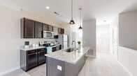 Located at 484 Greenmont Dr in Lewis Center, Ohio, this single-floor residence offers a thoughtfully designed layout with modern finishes throughout. The kitchen serves as a central highlight, showcasing rich dark cabinetry, light granite countertops, and a large center island with an integrated sink and pendant lighting overhead. Stainless steel appliances, including a range, microwave, and refrigerator, complete the functional and stylish cooking space. The kitchen flows seamlessly into the open living area, which is finished with light wood-style flooring and neutral-toned carpeting, creating a cohesive and inviting atmosphere. Natural light filters in through multiple windows fitted with blinds, brightening the common areas. The bedrooms are carpeted and feature clean, neutral walls with generous walk-in closets equipped with built-in shelving and hanging rods. A well-sized hallway connects the rooms, adding to the open feel of the floor plan. The bathroom is finished with light wood-look flooring, a dark vanity with granite countertop, a large mirror with elegant lighting above, and a window that brings in additional natural light. Throughout the home, consistent use of dark cabinetry, granite surfaces, and neutral tones creates a cohesive, contemporary aesthetic.