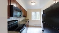 Located at 300 S Central Ave in Hartsdale, NY, this two-bedroom, one-and-a-half-bathroom residence offers a practical and comfortable single-floor layout in the heart of Westchester County. The kitchen is a functional highlight of the home, featuring rich dark wood cabinetry, granite countertops, a tiled backsplash, and a full suite of black appliances including an electric range, built-in microwave, dishwasher, and refrigerator. Light tile flooring runs throughout the kitchen, which is brightened by a window overlooking lush, tree-lined greenery — bringing a sense of nature indoors. A baseboard heating unit ensures comfort throughout the seasons. The neutral, light-toned walls create a clean and versatile backdrop throughout the residence, allowing for a variety of interior styles. With two well-proportioned bedrooms and a full bath complemented by a convenient half bath, the layout is well-suited for both everyday living and hosting. Situated in Hartsdale, residents enjoy easy access to local shops, dining, and Metro-North rail service, making this an ideal home for those seeking suburban comfort with urban connectivity.