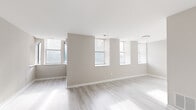 Located on Delmar Boulevard in St. Louis, Missouri, this single-floor unit offers a well-designed, light-filled layout with a cohesive modern aesthetic throughout. The main living area is expansive and open, featuring light-toned hardwood flooring and neutral warm-gray walls that create a calm, airy atmosphere. A row of multiple windows lines the living space, inviting generous natural light and enhancing the sense of openness.

A distinctive curved bay window nook adds a charming architectural detail to one of the rooms, with two windows framing views of the surrounding neighborhood. Additional rooms feature large windows with street-facing views, maintaining the bright character found throughout the unit.

The kitchen is efficiently laid out, equipped with warm wood cabinetry, light stone-patterned countertops, and stainless steel appliances including a refrigerator and oven range. Light hardwood flooring continues seamlessly from the living areas into the kitchen.

The bathroom features warm terracotta-toned tile flooring, a full tub-shower combination with white tile surround, and a clean white vanity with ample counter space. Clean white trim and neutral wall tones tie the space together, creating a consistent and polished finish throughout the entire unit.
