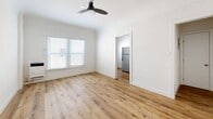 Located at 132 S Westmoreland Ave in the heart of Los Angeles, CA, this efficiently designed single-floor unit offers a well-organized layout comprising a living room, kitchen, bathroom, hallway, and two closets. Throughout the space, warm-toned hardwood-style flooring provides a cohesive and inviting foundation.

The living room is bright and airy, featuring white walls, a ceiling fan, and window blinds that allow for natural light control. The clean, minimal aesthetic makes the space feel open and versatile. An open doorway connects the living area directly to the kitchen, which is equipped with a stainless steel refrigerator and benefits from its own window, keeping the area naturally lit and ventilated.

The bathroom is a standout feature, showcasing large-format dark marble-style tile surrounding a soaking tub and shower combination. A white vanity and natural light from a window complete the polished, modern look of this room.

Storage is well-addressed with two dedicated closets. One functions as a walk-in closet with wrap-around hanging rods on multiple walls, offering generous organizational capacity. The second closet provides additional storage accessible from the main living area. A connecting hallway ties the rooms together efficiently. The unit's crisp white walls and consistent flooring throughout create a cohesive, move-in-ready environment.