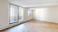 Located on the 7th floor at 43 Forest Ave in Hamilton, Ontario, this one-bedroom, one-bathroom unit offers a practical and well-appointed layout across a single floor. Light hardwood flooring runs throughout, lending warmth and continuity to the space.

The open-concept living room is a standout feature, bathed in natural light from large sliding glass doors that open to a private balcony with views of the surrounding cityscape. An additional window further enhances the bright, airy atmosphere. Baseboard heating runs along the perimeter, providing efficient warmth.

The galley-style kitchen is efficiently designed with white shaker cabinetry, dark countertops, a classic subway tile backsplash, and stainless steel appliances including a full-size refrigerator, electric range, and over-the-range microwave. A stainless steel sink completes the functional workspace.

The bedroom is a comfortable, well-lit room featuring a large sliding-door closet for ample storage. A window allows natural light to filter in, and the room connects conveniently to the main hallway.

The bathroom features a full soaker tub framed by crisp white subway tile surround, offering a clean and timeless aesthetic. A hallway connects all rooms, ensuring a logical and efficient flow throughout the unit.