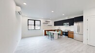 Located at 4614 John F Kennedy Blvd in Union City, NJ, this thoughtfully designed two-bedroom, one-bathroom residence offers a clean, modern aesthetic across a well-proportioned single-floor layout. Light hardwood-style flooring runs throughout, anchoring the bright, white-walled interiors and creating a cohesive, contemporary feel.

The kitchen is a standout feature, showcasing bold dark upper cabinetry contrasted by warm wood-tone lower cabinets, a striking marble-veined quartz backsplash and countertops, and a full suite of stainless steel appliances including a refrigerator, range, microwave, and dishwasher. A marble-top dining table with space for four sits adjacent, making the kitchen an ideal hub for everyday living.

The open living area is bright and airy, equipped with a wall-mounted mini-split HVAC unit for year-round climate control. Both bedrooms are well-sized — the primary offering ample room — each featuring black-framed windows that bring in natural light and views of the surrounding neighborhood, along with closets fitted with sleek white panel doors and matte black hardware.

The bathroom is elegantly finished with large-format marble-style wall tiles surrounding a soaking tub with shower, complemented by neutral stone-toned floor tiles for a spa-like ambiance.