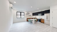 Located at 4614 John F Kennedy Blvd in Union City, NJ, this thoughtfully designed two-bedroom, one-bathroom residence offers a clean, modern aesthetic across a well-proportioned single-floor layout. Light hardwood-style flooring runs throughout, anchoring the bright, white-walled interiors and creating a cohesive, contemporary feel.

The kitchen is a standout feature, showcasing bold dark upper cabinetry contrasted by warm wood-tone lower cabinets, a striking marble-veined quartz backsplash and countertops, and a full suite of stainless steel appliances including a refrigerator, range, microwave, and dishwasher. A marble-top dining table with space for four sits adjacent, making the kitchen an ideal hub for everyday living.

The open living area is bright and airy, equipped with a wall-mounted mini-split HVAC unit for year-round climate control. Both bedrooms are well-sized — the primary offering ample room — each featuring black-framed windows that bring in natural light and views of the surrounding neighborhood, along with closets fitted with sleek white panel doors and matte black hardware.

The bathroom is elegantly finished with large-format marble-style wall tiles surrounding a soaking tub with shower, complemented by neutral stone-toned floor tiles for a spa-like ambiance.