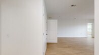 This single-floor residence in Danbury, CT offers a clean, modern aesthetic throughout its three bedrooms and two bathrooms. Light wood laminate flooring flows consistently across the living areas and bedrooms, creating a cohesive and bright interior. The open-concept kitchen and living room serve as the heart of the home, with the kitchen featuring warm cherry wood cabinetry, white countertops, black appliances including a range and built-in microwave, and a peninsula with a undermount sink and matte black faucet — ideal for both cooking and casual dining. The living area is spacious and open, filled with natural light. The generously sized primary bedroom includes a ceiling fan, two windows overlooking greenery, and an adjoining room providing added convenience. The secondary bedrooms are well-proportioned, each featuring large windows with blinds that invite natural light and outdoor views of surrounding trees. Both bathrooms are finished with tile flooring, warm wood vanities, white countertops, and large mirrors. The full bathroom includes a tub-shower combination. An in-unit washer is also present, adding everyday practicality to this thoughtfully designed home.