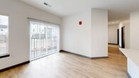 Located at Peninsula Pointe Circle in Lafayette, Indiana, this well-designed 2-bedroom, 1-bathroom unit offers a clean, modern aesthetic throughout. The open-concept kitchen is a standout feature, showcasing gray shaker-style cabinetry, white countertops, a central island, stainless steel appliances including a range, dishwasher, and refrigerator, and light wood-look flooring that extends into the living area. Recessed lighting brightens the kitchen space, adding to its contemporary feel. The living area features large sliding glass doors with vertical blinds, allowing abundant natural light and exterior views. Both bedrooms are carpeted and feature large windows with blinds that bring in natural light, and dark contrasting baseboards that complement the neutral walls. The primary bedroom includes a dedicated closet with built-in rod and shelving. The full bathroom is outfitted with a soaking tub and shower combination featuring a curved chrome rod, wood-look flooring, and clean white fixtures. A dedicated in-unit laundry room with full-size washer and dryer and a shelving unit adds everyday convenience. Gray panel-style interior doors are consistent throughout, contributing to a cohesive modern design.