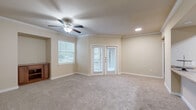This single-story, 2-bedroom, 2-bathroom home offers a thoughtfully designed layout that maximizes comfort and functionality. The living room is a standout space, featuring crown molding, plush carpeting, a ceiling fan with light fixture, and a set of French doors that invite natural light and provide outdoor access. A second window further brightens the room, creating an open and airy atmosphere.

The kitchen is accessible via a pass-through opening and features rich, dark wood cabinetry paired with a stainless steel dishwasher. A skylight overhead floods the kitchen and adjacent hallway with natural light, while durable hardwood-style flooring runs throughout these areas.

Both bedrooms are carpeted and well-lit, each equipped with a ceiling fan and window with blinds that frame views of surrounding greenery. The primary bedroom includes a built-in corner cabinet nook and crown molding, adding a refined architectural detail. The secondary bedroom offers a cozy, versatile layout with ample wall space.

Each bathroom is finished with white tile soaking tub-shower combinations accented by a decorative dark tile border, wood-style flooring, and warm wood cabinetry. The home also includes a dedicated laundry area and two closets, providing practical storage throughout.