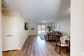 Located at 21495 LeMay Dr in Riverside, CA, this well-appointed single-story home offers a thoughtfully designed layout across one comfortable floor. The open-concept living and dining area is anchored by rich hardwood-style flooring, warm neutral wall tones, and a sliding glass door that fills the space with natural light and provides direct access to a private patio overlooking a lush green yard. The dining area flows seamlessly into the living room, creating an inviting space ideal for both everyday living and entertaining.

The kitchen features white cabinetry, granite countertops, a classic white undermount sink, and tile flooring — combining functionality with a clean, timeless aesthetic. A window above the sink brings in additional natural light.

The generously sized primary bedroom is carpeted for comfort and includes a large window that allows ample daylight. The home also boasts an impressive seven closets, providing exceptional storage throughout. The bathroom is well-equipped with a granite-topped vanity, a large mirror with Hollywood-style lighting, tile flooring, and a glass-enclosed shower and tub combination.

Outside, the stucco exterior with a tile roof is complemented by manicured landscaping and a walkway. The attached garage features an epoxy-coated floor and an automatic opener, adding practicality to this move-in-ready home.