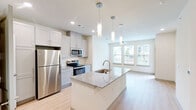 Located at 8025 Monty Stratton Pkwy in Greenville, TX, this well-appointed one-bedroom, one-bathroom residence combines modern design with functional living. The open-concept layout seamlessly connects the kitchen, dining, and living areas, all finished with light hardwood-style flooring that enhances the bright, airy atmosphere throughout.

The kitchen is a standout feature, boasting a large center island with a granite countertop and undermount sink, sleek gray shaker-style cabinetry, and a full suite of stainless steel appliances including a refrigerator, microwave, and electric range. Stylish pendant lighting above the island adds a contemporary touch, while large windows flood the living area with natural light and offer views of the surrounding neighborhood.

The bedroom is a comfortable retreat, featuring two windows with outdoor views, a ceiling fan, and light-toned flooring. A dedicated closet provides convenient storage space.

The bathroom is thoughtfully designed with a granite-topped vanity, light gray cabinetry, and a tiled tub-shower combination, all complemented by light hardwood-style flooring. The in-unit laundry room includes side-by-side washer and dryer units with built-in shelving for added functionality. A hallway connects all rooms, ensuring a practical and efficient floor plan throughout this well-designed residence.