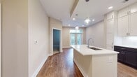 This compact yet well-designed apartment maximizes its 670 square feet of living space. The single-floor layout encompasses one bedroom, measuring a generous 190 square feet, along with two bathrooms for added convenience. The living area, as shown in the image, boasts beautiful wood-look flooring that extends throughout, creating a warm and inviting atmosphere. Recessed lighting in the textured ceiling provides ample illumination, while the neutral-toned walls offer a blank canvas for personalization. A standout feature is the set of French doors with transom windows above, leading to what appears to be a balcony or patio area. These doors not only allow natural light to flood the space but also provide a seamless indoor-outdoor connection. The apartment's efficient design includes a living room, kitchen, and a closet, ensuring all essential living spaces are accounted for within its compact footprint. This thoughtful layout makes the most of every square foot, creating a comfortable and functional living environment.