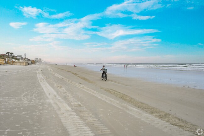 A person bikes on a sandy beach.