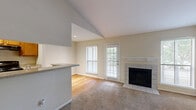 Located at 2200 Montgomery Park Blvd in Conroe, TX, this one-bedroom, one-bathroom residence offers a thoughtfully designed single-floor layout that maximizes comfort and functionality. The open-concept living, dining, and kitchen area serves as the heart of the home, anchored by a tile-surround wood-burning fireplace flanked by large windows that flood the space with natural light. Soft carpet covers the living area, while hardwood flooring extends through the kitchen and hallway, adding warmth and contrast throughout.

The kitchen features warm wood cabinetry, a granite-style countertop, a built-in sink, dishwasher, and range, all organized around a peninsula breakfast bar that opens to the living space. High ceilings in the main living area lend an airy, open feel.

The generously sized bedroom is carpeted and includes a ceiling fan with light fixture, a window with outdoor views, and access to a dedicated walk-in closet. The full bathroom is clean and functional, offering a tub/shower combo with white tile surround and wood cabinetry for storage.

A private balcony accessible from the living room overlooks a lush, tree-lined landscape, providing a peaceful outdoor retreat. The space also includes a hallway with built-in shelving for added storage.