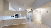 Located at 223 Lake Ridge Dr in Kalamazoo, Michigan, this single-floor home offers a thoughtfully designed open layout with a variety of notable architectural details. The living room serves as a central gathering space, highlighted by soaring vaulted ceilings, plush carpeting, a classic fireplace with a white mantel, and a sliding glass door that invites natural light and outdoor views. The kitchen is efficiently arranged with a peninsula counter, crisp white cabinetry with modern hardware, light countertops, and black appliances including an electric range and an over-the-range microwave. Wood-look flooring in the kitchen and entry areas transitions seamlessly to soft carpet in the living and sleeping areas. The bedrooms are generously sized with large windows that frame views of the surrounding neighborhood and mature trees, filling the rooms with natural light. The bathroom features a full tub-shower combo with tile surround, a white vanity with ample storage, and light wood-look flooring. Throughout the home, a neutral color palette of soft grays and whites creates a clean, cohesive aesthetic. A front entry door with a decorative transom window adds a welcoming touch to the overall design of this well-maintained Kalamazoo residence.