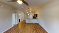 This single-floor residence at 3000 Twyckenham Blvd in Lafayette, Indiana, offers a well-designed open-concept layout that seamlessly connects the living, dining, and kitchen areas. The main living space is highlighted by vaulted ceilings and rich hardwood-style flooring, creating a warm and inviting atmosphere. A ceiling fan with integrated lighting adds both functionality and style to the area, while a window at the far end allows natural light to fill the room.

The kitchen is a standout feature, boasting dark espresso cabinetry with granite-style countertops, a breakfast bar peninsula with pendant lighting overhead, and a full suite of stainless steel appliances including a refrigerator, range, and microwave. The open pass-through design keeps the kitchen connected to the living space, making it ideal for everyday use and entertaining.

The bedrooms feature plush carpeting, ceiling fans, and windows with blinds that provide natural light and outdoor views. The neutral, warm-toned walls create a calm and comfortable environment throughout.

The bathrooms are finished with dark wood vanities topped with granite-style counters and hardwood-style flooring that carries through from the main living areas. One bathroom includes a full soaking tub with tiled surround, while another offers a vanity and toilet in a clean, functional layout. The overall design is cohesive, modern, and move-in ready.
