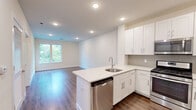 Located at 41 W Prospect St in Waldwick, NJ, this well-appointed one-bedroom, one-bathroom residence offers a thoughtfully designed single-floor layout with a clean, modern aesthetic throughout. Warm hardwood-style flooring flows consistently across the living spaces, complemented by neutral cream-toned walls and recessed lighting that create a bright, welcoming ambiance.

The open-concept kitchen and living area serves as the heart of the home. The kitchen is outfitted with crisp white shaker cabinetry extending to the ceiling for ample storage, a classic subway tile backsplash, quartz countertops, and a full suite of stainless steel appliances including a gas range, built-in microwave, and refrigerator. A peninsula with an undermount sink adds both prep space and a natural divide between the kitchen and the living area.

The generously sized bedroom features a large window overlooking lush, mature greenery, filling the room with natural light and peaceful outdoor views. It connects directly to a dedicated walk-in closet equipped with multi-level wire shelving for organized storage. The bathroom is finished with marble-look tile flooring, a white shaker vanity with a quartz countertop, a large mirror, and polished chrome fixtures. The overall design is cohesive, modern, and move-in ready.