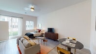 This open-concept studio is thoughtfully designed to maximize functionality within a single, flowing living space. Light-toned hardwood-style flooring runs throughout, creating a cohesive and airy feel. The main living area seamlessly integrates a sleeping zone, living area, and dining space, all illuminated by a ceiling fan with integrated lighting. Large windows with plantation shutters and a glass-panel balcony door allow ample natural light while offering views of the surrounding exterior.

The kitchen is neatly positioned along one wall and features white cabinetry extending to the ceiling, stainless steel appliances including an electric range, over-the-range microwave, and dishwasher, complemented by granite-style countertops and a single-basin stainless steel sink. Storage is addressed by a closet with double doors near the sleeping area.

The bathroom offers a vanity with granite-style countertop and undermount sink, white cabinetry, tile flooring, and a shower-tub combination with a curtain enclosure. Clean, neutral wall tones throughout the unit contribute to a modern and cohesive aesthetic, while the open layout ensures the space feels open and welcoming.