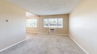 Located at 2400 Arden Way in the Arden-Arcade neighborhood of Sacramento, CA, this one-bedroom, one-bathroom unit offers a practical and comfortable single-floor layout. The living room is generously proportioned, featuring warm beige walls, soft carpeted flooring, a textured ceiling, and multiple windows fitted with horizontal blinds that allow ample natural light while providing outdoor views of the surrounding neighborhood. A wall-mounted HVAC unit ensures year-round climate control. The bedroom is a well-sized private retreat, also carpeted, with a window offering natural light and a peaceful outdoor view. It connects to a dedicated walk-in closet outfitted with built-in shelving and hanging rods, providing organized and efficient storage space. The galley-style kitchen is efficiently designed, featuring white cabinetry, granite-look countertops, a stainless steel sink, and white appliances including a gas range and refrigerator, all set on light wood-look flooring. The bathroom is clean and functional, offering a full tub-shower combo with white tile surround, a white vanity with under-sink storage, and light flooring. Consistent warm beige tones and neutral finishes throughout the unit create a cohesive and inviting atmosphere.