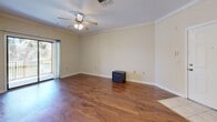 Located at 10011 Balaye Run Dr in Tampa, FL, this single-story home offers five bedrooms and two full bathrooms across a well-organized floor plan. The living room is a welcoming focal point, featuring warm hardwood flooring, crown molding, a ceiling fan with light fixture, and sliding glass door access that brings in natural light and outdoor views. A dedicated dining area is accented by an elegant chandelier and matching crown molding, adding a refined touch to the space. The kitchen is thoughtfully appointed with light wood cabinetry, granite countertops, tile backsplash, and black appliances including an electric range and refrigerator, complemented by a convenient breakfast bar with a double sink. The primary bedroom provides generous proportions, plush carpeting, a ceiling fan, dual closets, and direct access to an en suite bathroom. The bathrooms are finished with granite-topped white vanities, tile flooring, and large mirrors. Additional bedrooms share similar carpet flooring and ceiling fans, with select rooms featuring windows that invite natural light. Crown molding is a consistent architectural detail carried throughout the home, lending a cohesive and polished character to every room.