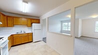 Located at 8 Isabel Lane, Unit 110 in Monticello, NY, this one-bedroom, one-bathroom unit offers a well-organized, single-floor layout designed for comfortable everyday living. The kitchen is a functional highlight, featuring warm honey-toned wood cabinetry with brass hardware, white countertops, a white tile backsplash, and white appliances including a refrigerator and electric range. Light tile flooring completes the kitchen's clean, practical aesthetic. The living room is bright and inviting, with large windows that welcome natural light and views of the surrounding greenery. Soft wall-to-wall carpeting extends through the living areas and into the spacious bedroom, which offers generous square footage, large windows, and a pass-through closet providing additional storage access. A dedicated walk-in closet features built-in wire shelving systems, maximizing storage capacity. The bathroom is finished with light tile flooring and includes a glass-door shower stall and accessibility-friendly grab bars. Throughout the unit, neutral white walls and clean lines create a consistent, move-in-ready atmosphere. The layout flows efficiently between rooms, making the most of the available space while maintaining a comfortable and functional living environment.