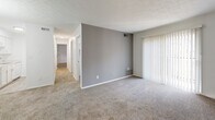 Located at 800 Valley Brook Dr in Milford, Ohio, this single-floor unit offers a straightforward, functional layout designed for comfortable everyday living. The floor plan, visible through the 3D model, reveals a series of well-proportioned rooms connected by a central hallway, providing clear separation between living and private spaces.

The main living area features neutral-toned carpeting and a textured ceiling, with a large sliding glass door fitted with vertical blinds that allows natural light to filter in. A gray accent wall adds a subtle visual contrast to the otherwise crisp white walls. The hallway extends toward the bedrooms, maintaining a consistent design aesthetic throughout.

The bedrooms are carpeted and finished with white walls and textured ceilings. Each room includes a window with horizontal blinds offering views of the surrounding greenery, contributing a sense of openness to each space.

Two bathrooms serve the unit. One features wood-look vinyl flooring, a white vanity, and a tub-shower combination with white tile surround. The second bathroom similarly features wood-look flooring, a white vanity, toilet, and an over-toilet storage cabinet with brass hardware. Both bathrooms maintain a clean, cohesive white palette throughout.