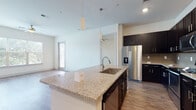 Located at 2300 Wolf Ranch Pkwy in Georgetown, Texas, this single-floor residence offers a well-designed open-concept layout that seamlessly connects the kitchen, dining, and living areas. The kitchen is a standout feature, showcasing dark espresso cabinetry, granite countertops, a subway tile backsplash, and a full suite of stainless steel appliances including a French door refrigerator, range, and over-the-range microwave. A large center island with a granite surface and undermount sink provides additional workspace and serves as a natural gathering point, illuminated by pendant lighting above. Wood-look flooring extends throughout the main living areas, complementing the bright, neutral color palette. The spacious living room benefits from large windows and a ceiling fan, inviting abundant natural light. The bedrooms feature plush carpeting, ceiling fans, and windows with outdoor views. The bathrooms are finished with matching dark cabinetry, granite vanity tops, and light tile flooring, maintaining a cohesive aesthetic throughout. A dedicated laundry room with shelving and hookups adds everyday convenience. The overall ambiance is clean, modern, and move-in ready.