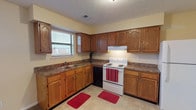 This single-story residence on Shawnee Trail offers a practical and well-organized layout across its living spaces. The kitchen is a notable feature, equipped with warm oak cabinetry extending to the ceiling for generous storage, dark-toned laminate countertops, a double sink positioned beneath a window, and white appliances including an electric range and refrigerator. Light tile flooring grounds the kitchen area, which opens toward the main living space finished in neutral carpet.

The bedrooms are carpeted and bathed in natural light through blinded windows, maintaining a calm, neutral palette with cream-toned walls and textured ceilings. The primary bedroom is particularly spacious, featuring a ceiling fan, direct closet access, and a walk-in closet outfitted with wire shelving systems for organized storage. Additional bedrooms offer comfortable proportions and exterior views.

Two full bathrooms serve the home, each featuring a tub-shower combination, vanity with storage, toilet, and tile flooring. The overall layout, as shown in the floor plan, flows efficiently with well-connected rooms and multiple closets providing practical storage throughout. Textured ceilings are consistent across the home, contributing to its cohesive character.