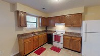 This single-story residence on Shawnee Trail offers a practical and well-organized layout across its living spaces. The kitchen is a notable feature, equipped with warm oak cabinetry extending to the ceiling for generous storage, dark-toned laminate countertops, a double sink positioned beneath a window, and white appliances including an electric range and refrigerator. Light tile flooring grounds the kitchen area, which opens toward the main living space finished in neutral carpet.

The bedrooms are carpeted and bathed in natural light through blinded windows, maintaining a calm, neutral palette with cream-toned walls and textured ceilings. The primary bedroom is particularly spacious, featuring a ceiling fan, direct closet access, and a walk-in closet outfitted with wire shelving systems for organized storage. Additional bedrooms offer comfortable proportions and exterior views.

Two full bathrooms serve the home, each featuring a tub-shower combination, vanity with storage, toilet, and tile flooring. The overall layout, as shown in the floor plan, flows efficiently with well-connected rooms and multiple closets providing practical storage throughout. Textured ceilings are consistent across the home, contributing to its cohesive character.