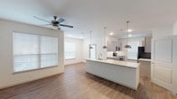Located in Houston, TX (77396), this single-story residence offers a clean, contemporary design throughout. The open-concept living and kitchen area is anchored by a large central island topped with light granite countertops, a stainless steel sink, and stylish pendant lighting. Wood-look flooring extends throughout the main living spaces, complemented by a ceiling fan and multiple windows with blinds that allow ample natural light to fill the room.

The kitchen is well-appointed with gray shaker-style cabinetry extending to the ceiling, matching light granite countertops, a white subway tile backsplash, and a full suite of stainless steel appliances including a range, over-the-range microwave, and refrigerator. The galley-style layout provides generous counter and storage space.

The bedrooms feature plush carpeting, ceiling fans with light fixtures, and windows that bring in natural light. One bedroom includes a spacious walk-in closet outfitted with multi-tiered shelving, hanging rods, and built-in shelving units, offering exceptional organization potential.

The bathrooms are finished with wood-look flooring, gray cabinetry with granite countertops, white subway-tiled tub and shower combinations with brushed nickel fixtures and grab bars, lending a polished, cohesive aesthetic throughout the home.