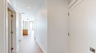 This contemporary Nashville residence offers a thoughtfully designed single-floor layout with 2 bedrooms and 3 bathrooms, delivering a refined urban living experience. The open-concept design is anchored by light hardwood flooring and crisp white walls that flow seamlessly throughout. Floor-to-ceiling windows with dark frames are a defining architectural feature, flooding the space with natural light and framing sweeping panoramic views of the Nashville skyline and surrounding neighborhoods. The kitchen is outfitted with warm wood cabinetry, a marble-style backsplash, stainless steel appliances including a gas range and side-by-side refrigerator, and a center island. Each bedroom benefits from the dramatic window walls, with the primary suite offering a generous walk-in closet with built-in shelving. The primary bathroom features large-format slate tile flooring, a floating wood vanity with a white countertop, a glass-enclosed walk-in shower, and a window with city views. A compact powder bath with pedestal sink serves guests. The dedicated laundry room houses a full-size front-loading washer and dryer. Two closets provide ample storage, completing this well-appointed, light-filled urban home.