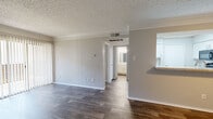 This single-story, 1-bedroom, 1-bathroom unit offers a practical and comfortable layout across a compact yet efficiently designed floor plan. The combined kitchen and living room serves as the heart of the space, where the living area features warm wood-look flooring, crown molding, a textured ceiling, and a dark-surround fireplace as a focal point. A sliding glass door floods the room with natural light and provides outdoor access. The kitchen is defined by white cabinetry, stone-look countertops with a breakfast bar overhang, subway tile backsplash, stainless steel appliances, and a skylight-style overhead panel that brightens the workspace.

The bedroom is generously sized with neutral tones, wood-look flooring, and a large window with blinds that allow for ample natural light. A spacious walk-in closet off the bedroom provides extensive shelving and hanging space for storage. The bathroom includes a full tub-shower combination with white tile surround, wood-look flooring, and a vanity with matching stone-look countertops. A dedicated laundry area and hallway complete the thoughtful layout. The entry area features a ceiling fan and crown molding, adding a finishing touch throughout.