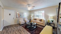 The Cosmopolitan Upgraded floor plan offers a thoughtfully designed single-story layout with two bedrooms and two full bathrooms. The living room serves as the heart of the home, featuring wood-style flooring, a ceiling fan, and large windows that invite abundant natural light and outdoor views, creating a bright and welcoming atmosphere. An adjacent dining area provides a cozy space for meals, accented by warm neutral tones and framed wall art. The galley-style kitchen is equipped with white cabinetry, light countertops, a double-basin sink, and a full suite of appliances, offering ample storage and prep space. Both bedrooms are carpeted for comfort and include ceiling fans and generously sized windows with outdoor views. Each bedroom features closet storage, while the second bedroom includes a dedicated reach-in closet. The two full bathrooms are finished with wide vanity counters, large mirrors with overhead lighting, and wood-style flooring. Throughout the residence, warm neutral wall tones provide a cohesive backdrop that complements the upgraded finishes, making this floor plan a comfortable and functional living option.
