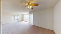 This single-floor unit offers a thoughtfully arranged layout with distinct living, sleeping, and functional zones. The main living area is generously proportioned, featuring neutral-toned wall-to-wall carpeting, a textured ceiling, and a ceiling fan with integrated lighting that provides both comfort and illumination. Multiple windows allow natural light to filter in, creating a bright and open atmosphere throughout the space.

The layout, as seen in the 3D floor plan, reveals several carpeted bedroom spaces, each offering ample room and access to closet storage. One bedroom features a large walk-in closet outfitted with dual hanging rods on opposing walls, maximizing storage capacity. A bedroom window frames an outdoor view, adding a sense of openness to the private sleeping areas.

The kitchen is equipped with dark-stained upper and lower cabinetry with gold hardware, contrasting against light-toned countertops. White appliances, including a gas range, dishwasher, and refrigerator, are included, along with a utility sink. Light vinyl flooring completes the functional space.

The bathroom features a wood-toned vanity with a single sink, a wall-length mirror, tile wainscoting, and small-format floor tile, offering a clean and practical design.