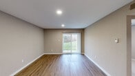 Located at 301 Martha Layne Collins Blvd in Highland Heights, Kentucky, this two-bedroom, one-bathroom single-floor unit offers a well-designed layout with a cohesive neutral color palette throughout. The combined kitchen and living area serves as the heart of the home, where warm wood-look flooring extends across the open space. A sliding glass door fitted with vertical blinds floods the living area with natural light and provides views of a lush green landscape. The kitchen features white shaker-style cabinetry, light quartz countertops, stainless steel appliances including a refrigerator, range, and microwave, and ample storage space. The primary bedroom is generously proportioned and includes access to a dedicated walk-in closet outfitted with wire shelving on multiple walls, offering excellent organization potential. The second bedroom features soft carpet flooring and a sliding closet. The bathroom is clean and functional, complete with a tub-shower combination, wood-look flooring, and a quartz-topped vanity. A dedicated laundry area adds everyday convenience. Recessed lighting, white trim, and warm-toned walls contribute to a bright, welcoming ambiance throughout the unit.