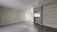 Located at 7500 Clarewood Dr in Houston, TX, this single-floor residence offers a thoughtfully arranged layout encompassing three bedrooms, a living room, dining room, pantry, and a dedicated closet. The interior is finished with wood-look flooring throughout the main living areas, lending a clean, contemporary aesthetic that complements the neutral warm-gray wall tones.

The open living and dining area is bright and welcoming, featuring a large window that draws in natural light and a pass-through window connecting to the kitchen. Built-in open shelving near the living area provides convenient display and storage space. A pendant light over the dining area adds a subtle design touch.

The galley-style kitchen is efficiently organized, featuring gray cabinetry on both sides, light stone-look tile flooring, ample counter space, and black appliances including a refrigerator, range, and dishwasher — making the most of the available space.

The generously sized primary bedroom offers plenty of room to furnish comfortably and includes a ceiling fan with light fixture. The well-appointed closet features a full built-in shelving and hanging system, offering excellent organization capacity. The additional bedrooms mirror the home's clean, neutral finishes, maintaining a cohesive look throughout.