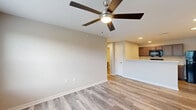 Located at 4115 Meadows Dr in Indianapolis, Indiana, this single-story, 3-bedroom, 2-bathroom home offers a well-designed layout with modern finishes throughout. Light gray luxury vinyl plank flooring runs through the main living areas, complemented by neutral-toned walls that create a clean, contemporary aesthetic.

The kitchen is a functional highlight, featuring rich dark taupe cabinetry with brushed nickel hardware, light quartz countertops, a peninsula breakfast bar, and black appliances including a refrigerator, range, and over-the-range microwave. Recessed lighting keeps the space bright and practical.

The living room is open and airy, with a ceiling fan and a large window allowing natural light and outdoor views. The three bedrooms are carpeted for comfort, each equipped with ceiling fans and closet storage. The spacious primary bedroom includes a sliding closet and an adjacent bathroom with a walk-in shower. The second bathroom features a full soaking tub-shower combination, both finished in crisp white surrounds with wood-look flooring.

A dedicated laundry room houses a full-size top-loading washer and dryer with overhead shelving for additional storage. Throughout the home, clean lines, neutral palettes, and consistent finishes contribute to a cohesive and move-in-ready living environment.