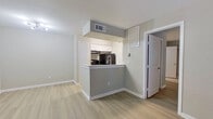 This well-maintained single-floor residence offers a thoughtfully designed open-concept layout that seamlessly connects the kitchen and living area. The kitchen is anchored by a wraparound peninsula with light-toned countertops, white upper cabinetry, a stainless steel sink, and dark appliances including a refrigerator and range with overhead ventilation. A soffit detail above the kitchen adds architectural definition to the space.

The living area is generously proportioned, featuring light wood-look luxury vinyl plank flooring that runs consistently throughout the unit, soft neutral wall tones, and clean white baseboards. A ceiling fan with integrated lighting serves the main living space, while a window with horizontal blinds allows for natural light and privacy control.

The bedrooms are comfortably sized with the same durable flooring, large windows for natural light, and neutral warm-toned walls. One bedroom features access to a dedicated walk-in closet with built-in shelving, alongside an additional standard closet — providing substantial storage capacity.

The bathroom is efficiently appointed with a single-sink vanity featuring white cabinetry and a framed mirror, a full tub-shower combination with white surround, and coordinating fixtures throughout. The overall design of the unit reflects a clean, contemporary aesthetic with functional finishes suited for comfortable everyday living.