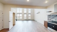 This thoughtfully designed two-floor residence offers a bright and open living experience defined by clean lines and contemporary finishes. The main living area is a standout feature, boasting dramatic double-height ceilings and a wall of floor-to-ceiling windows that flood the space with natural light and provide expansive outdoor views. Light-toned wood-style flooring runs throughout both levels, creating a cohesive and airy aesthetic. A wall-mounted split HVAC unit and baseboard heating ensure year-round comfort in the living area. The kitchen is well-appointed with warm wood cabinetry, a gray tile backsplash, stone countertops, and a full suite of stainless steel appliances including a refrigerator, electric range with a stainless steel hood, and dishwasher. A half bath is conveniently located on the lower level. The upper floor hosts the bedrooms, each featuring ceiling fans and generous closet space. One bedroom includes a spacious walk-in closet with built-in shelving, while another offers a large sliding-door closet. A full bathroom on this level features a walk-in shower, vanity with stone countertop, and wood-style tile flooring. The staircase connects both floors with an open railing design, reinforcing the sense of space throughout this well-appointed residence.