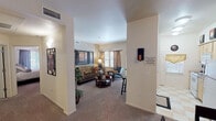 Located at 700 E Rodeo Rd in Casa Grande, Arizona, this single-floor residence offers a thoughtfully designed layout that balances comfort and functionality. The living room serves as the heart of the home, featuring warm neutral tones, plush carpeting, and generous natural light streaming through large windows dressed with elegant draping curtains. The open sightlines from the entry create an inviting flow throughout the space.

The kitchen is equipped with a double-basin sink, ample cabinetry with light wood finishes, dark laminate countertops, and a classic checkered tile floor. A window above the counter brings in additional natural light, making the space feel bright and practical.

The bedrooms are generously sized, each featuring plush carpeting, ceiling fans, and vaulted or elevated ceiling lines that enhance the sense of space. One bedroom showcases a calming blue accent wall, while another offers a sophisticated gray palette. Both bedrooms include closet storage.

Two full bathrooms provide functional amenities, each with a shower-tub combination. The neutral color schemes and clean finishes throughout maintain a consistent, understated aesthetic. The floorplan model confirms a well-organized layout with distinct zones for living, sleeping, and dining, making this residence a comfortable and practical home in the Arizona desert.