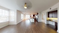 This well-appointed single-floor residence offers a thoughtfully designed open-concept layout that seamlessly connects the living, dining, and kitchen areas. Rich hardwood-style flooring flows throughout the main living spaces, complemented by neutral tones and abundant natural light streaming through multiple windows with horizontal blinds. Ceiling fans in the living and bedroom areas add both function and style.

The kitchen is a standout feature, showcasing dark espresso cabinetry, granite countertops, a decorative mosaic tile backsplash, and a full suite of stainless steel appliances including a refrigerator with ice maker, range, microwave, and dishwasher. A central island with a quartz-style countertop and pendant lighting overhead provides additional prep space and casual seating. Track lighting further illuminates the workspace.

The bedroom is carpeted for comfort and includes a ceiling fan, access to a private balcony through a glass door, and ample natural light. The primary bathroom features dark wood vanity cabinetry with granite countertops, a large mirror, tile flooring, and access to a walk-in closet. A second full bathroom includes a tub-shower combination and matching vanity finishes, maintaining a cohesive design throughout the home.