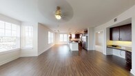 This well-appointed single-floor residence offers a thoughtfully designed open-concept layout that seamlessly connects the living, dining, and kitchen areas. Rich hardwood-style flooring flows throughout the main living spaces, complemented by neutral tones and abundant natural light streaming through multiple windows with horizontal blinds. Ceiling fans in the living and bedroom areas add both function and style.

The kitchen is a standout feature, showcasing dark espresso cabinetry, granite countertops, a decorative mosaic tile backsplash, and a full suite of stainless steel appliances including a refrigerator with ice maker, range, microwave, and dishwasher. A central island with a quartz-style countertop and pendant lighting overhead provides additional prep space and casual seating. Track lighting further illuminates the workspace.

The bedroom is carpeted for comfort and includes a ceiling fan, access to a private balcony through a glass door, and ample natural light. The primary bathroom features dark wood vanity cabinetry with granite countertops, a large mirror, tile flooring, and access to a walk-in closet. A second full bathroom includes a tub-shower combination and matching vanity finishes, maintaining a cohesive design throughout the home.