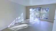 This two-floor residence offers a clean, modern aesthetic defined by neutral tones and carefully selected finishes throughout. The main living area immediately draws attention with its light-toned hardwood flooring that reflects an abundance of natural light, creating a warm and airy atmosphere. Large sliding glass doors fitted with vertical blinds serve as a prominent architectural feature, opening the space to outdoor views while flooding the interior with sunlight. The smooth white ceilings and neutral beige walls provide a versatile, understated backdrop well-suited to a variety of interior styles. The open layout of the living area contributes to a sense of spaciousness and easy flow between areas. Baseboards and trim are cleanly finished, adding a polished detail to the overall design. Across the two floors, the residence maintains a consistent design language — bright, functional, and well-appointed. The interplay of natural light with the light flooring and pale walls gives the entire space a refreshing, open quality that makes it feel welcoming and comfortable throughout the day.