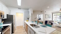 Located at 1001 East Playa Del Norte Drive in Tempe, Arizona, this well-designed 2-bedroom, 1-bathroom residence offers a thoughtful single-floor layout with clean, contemporary finishes throughout. The open-concept kitchen and living area serves as the heart of the home, anchored by a sleek peninsula with a white quartz countertop, stainless steel sink, and bar seating for three. The kitchen is equipped with stainless steel appliances — including a refrigerator, range, and microwave — complemented by gray shaker-style cabinetry, a subway tile backsplash, and a skylight that fills the space with natural light. Wood-look flooring flows seamlessly throughout, tying the spaces together with a warm, cohesive aesthetic. The living area features bright white walls and offers a relaxed, inviting atmosphere. Both bedrooms are comfortably scaled, each with a ceiling fan, natural light from windows with outdoor views of greenery, and wood-look flooring. A walk-in closet provides ample storage. The full bathroom includes a single vanity with a large mirror, quartz countertop, and a tub-shower combination. A dedicated laundry area with a washer and dryer completes the practical offerings of this efficient and stylish Tempe residence.