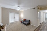 This well-appointed 2-bedroom, 2-bathroom unit in Huffman, TX offers a practical and comfortable single-floor layout. The living room is a welcoming space featuring crown molding, plush carpet, a ceiling fan, and French doors that invite natural light. The galley-style kitchen is efficiently designed with warm wood-toned cabinetry, dark countertops, wood-look flooring, and black appliances, including a full-size refrigerator and dishwasher, with direct access to a utility room. Both bedrooms are comfortably sized, carpeted, and equipped with ceiling fans and windows with blinds. The primary bedroom benefits from a dedicated walk-in closet with wire shelving spanning three walls, providing generous storage. The two bathrooms mirror each other in style, each featuring wood-look flooring, warm wood cabinetry, and a shower-tub combination. One bathroom includes an overhead cabinet above the toilet, while the other features a long vanity with an extended countertop and large mirror. A separate utility room adds further practicality to this thoughtfully arranged home.