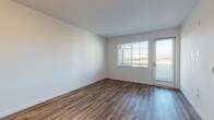 Located along Bollinger Canyon Road in San Ramon, CA, this well-designed single-floor unit offers a clean, modern aesthetic throughout. The open living area is finished with rich wood-style flooring that flows seamlessly from room to room, creating a warm and cohesive feel. Large windows fitted with horizontal blinds allow abundant natural light to fill the space, while a glass-paneled door opens to an outdoor patio with pleasant views of the surrounding landscape.

The kitchen is thoughtfully appointed with dark espresso cabinetry, crisp white countertops, and stainless steel appliances including a gas range and over-the-range microwave. A peninsula counter provides additional workspace and a natural transition into the living area. Built-in closet and shelving storage are conveniently integrated near the main living space.

The bedrooms offer plush wall-to-wall carpeting and are generously sized, each featuring dual windows that bring in ample daylight and scenic outdoor views. The bathroom is clean and functional, complete with a full soaking tub and shower combination, chrome fixtures, and wood-style flooring that ties the space together. The unit's bright white walls and neutral palette throughout create a fresh, move-in-ready environment.