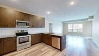 Located at 15309 Maple Island Rd in Burnsville, Minnesota, this well-appointed two-bedroom, two-bathroom residence offers a thoughtfully designed single-floor layout with a clean, modern aesthetic throughout. The open-concept kitchen is a standout feature, showcasing rich dark wood cabinetry, granite countertops, a subway tile backsplash, stainless steel appliances including a refrigerator, range, microwave, and dishwasher, and a peninsula with a built-in sink — ideal for both cooking and entertaining. The kitchen flows seamlessly into the living area, which is bathed in natural light from large windows and features sleek hardwood-style plank flooring. A sliding door provides access to an outdoor space. The primary bedroom offers plush carpeting and direct access to a dedicated walk-in closet with wire shelving, as well as a private en-suite bathroom featuring a granite-topped vanity with dark wood cabinetry and modern fixtures. The second bedroom is equally comfortable, with carpeted flooring and a bright window overlooking the surrounding neighborhood. A second walk-in closet provides additional storage. The dedicated in-unit laundry room includes a full-size washer and dryer with overhead wire shelving, adding everyday convenience. Neutral tones and consistent finishes create a cohesive and inviting ambiance throughout the entire space.
