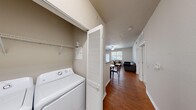 Located at Jefferson Commons in Kalamazoo, MI, this single-floor unit offers four bedrooms and five bathrooms within a well-organized layout. The living room serves as the central gathering space, featuring rich hardwood-style flooring, a ceiling fan, and large windows alongside a glass door that invite natural light and provide outdoor views, creating an open and airy atmosphere. The kitchen runs in a galley-style configuration, equipped with light wood cabinetry, dark granite-style countertops, a full-size refrigerator, dishwasher, and additional cabinetry space — practical and efficiently arranged. A dedicated in-unit laundry area with a full-size washer is tucked behind louvered doors, adding everyday convenience. Each bedroom features carpeted flooring, ceiling fans or pendant lighting, and ample closet space, with select rooms offering sliding mirrored closet doors and windows with natural light. The bathrooms maintain a consistent design with wood-style tile flooring, tub-shower combinations featuring white tile surrounds accented by a decorative black-and-tan tile border, and light wood vanity cabinetry with granite-style countertops. The overall aesthetic is clean and neutral, providing a comfortable and functional living environment.