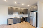 Located at 9420 Grand Blvd in Upper Marlboro, MD, this well-appointed 2-bedroom, 2-bathroom residence offers a thoughtfully designed single-floor layout that maximizes every inch of space. Light-toned luxury vinyl plank flooring flows seamlessly throughout, complementing the clean, modern aesthetic defined by crisp white walls and bright recessed lighting.

The open-concept living, dining, and kitchen area serves as the heart of the home. The kitchen is a standout feature, boasting slate-gray shaker-style cabinetry, white quartz countertops, a classic subway tile backsplash, and a full suite of stainless steel appliances including a refrigerator, range, built-in microwave, and dishwasher — ideal for both everyday cooking and entertaining.

Both bedrooms are well-proportioned and bathed in natural light, with the primary bedroom offering generous closet space. The two bathrooms mirror each other in design, each featuring subway-tiled tub-and-shower combinations, gray vanities with quartz countertops, and large mirrors with modern chrome fixtures. Additional highlights include six closets providing ample storage, a dedicated laundry area, and a central hallway connecting all rooms with ease. The overall ambiance is clean, contemporary, and move-in ready.