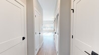 Located at 50 Hazel Dr in Cheshire, CT, this efficiently designed single-floor unit offers a thoughtfully laid-out living space with contemporary finishes throughout. Light wood-tone flooring runs seamlessly across the entire unit, contributing to a clean, cohesive aesthetic.

The kitchen is a standout feature, outfitted with white shaker-style cabinetry, granite countertops, a classic subway tile backsplash, and a full suite of stainless steel appliances — including a refrigerator, electric range, microwave, and dishwasher. A wall-mounted mini-split HVAC unit ensures year-round climate control.

A well-lit hallway connects the main living area to the rest of the unit, flanked by louvered closet doors that provide ample storage. The hallway leads to a bright, open living area featuring a large window that floods the space with natural light and offers views of the surrounding landscape with fall foliage.

The bathroom is finished in neutral tones and includes a white vanity, a bathtub with shower, grab bars for added accessibility, and wood-look tile flooring. The overall design palette — soft grays, crisp whites, and warm wood tones — creates a clean, modern ambiance that is both functional and welcoming.